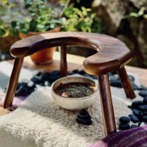 Half moon, u-shaped stool disassembled and showing the underside. Dark-coloured walnut wood.