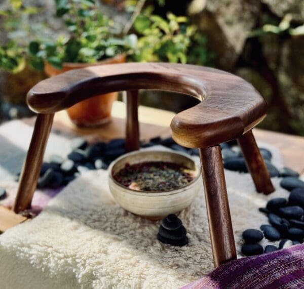 Half moon, u-shaped stool disassembled and showing the underside. Dark-coloured walnut wood.